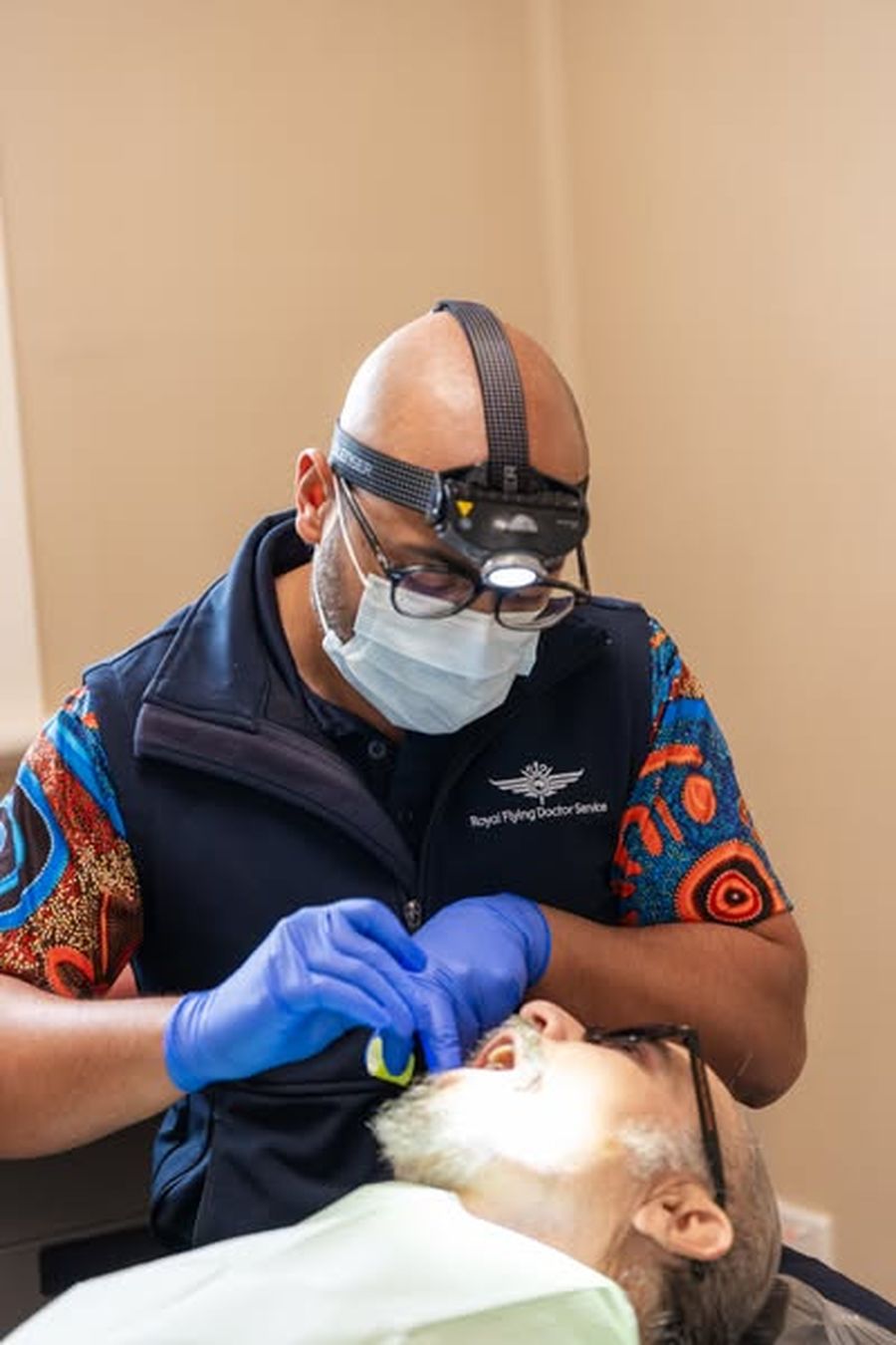 Dr Vai is pictured treating a patient in Alice Springs with an RFDS dental assistant at his side