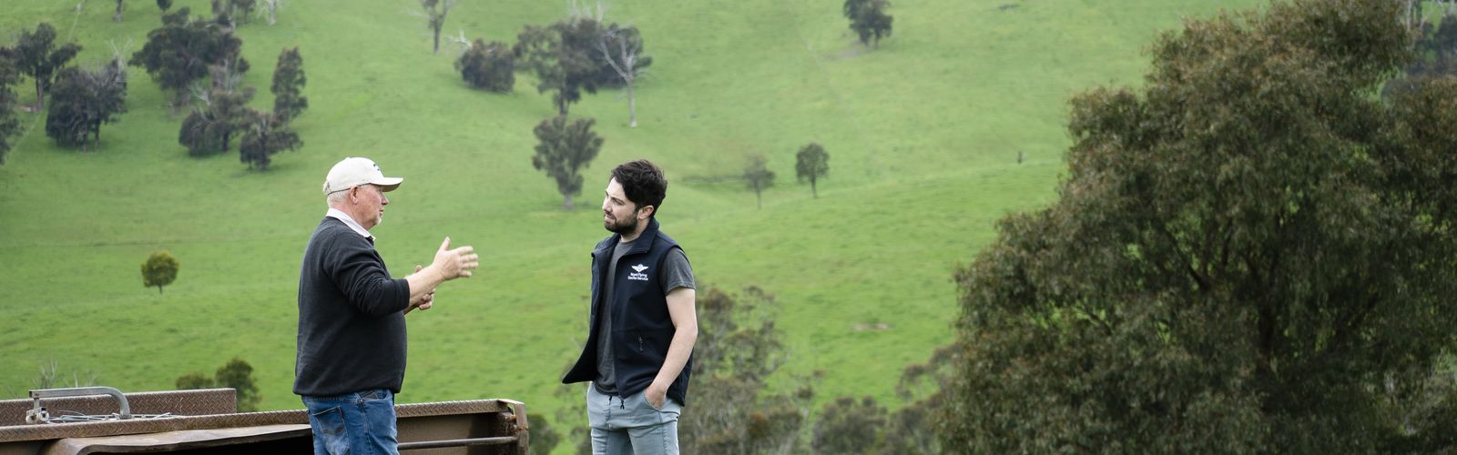 An RFDS staff member and a farmer stand in a field talking.