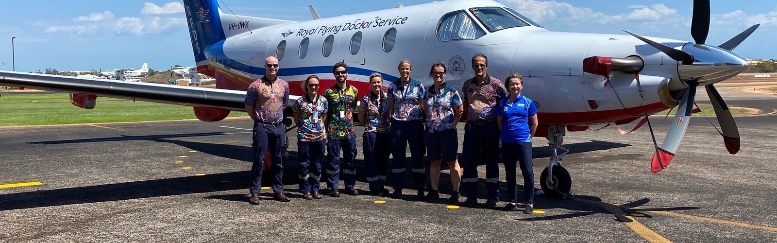 Community members gather around an RFDS plane on a dirt runway