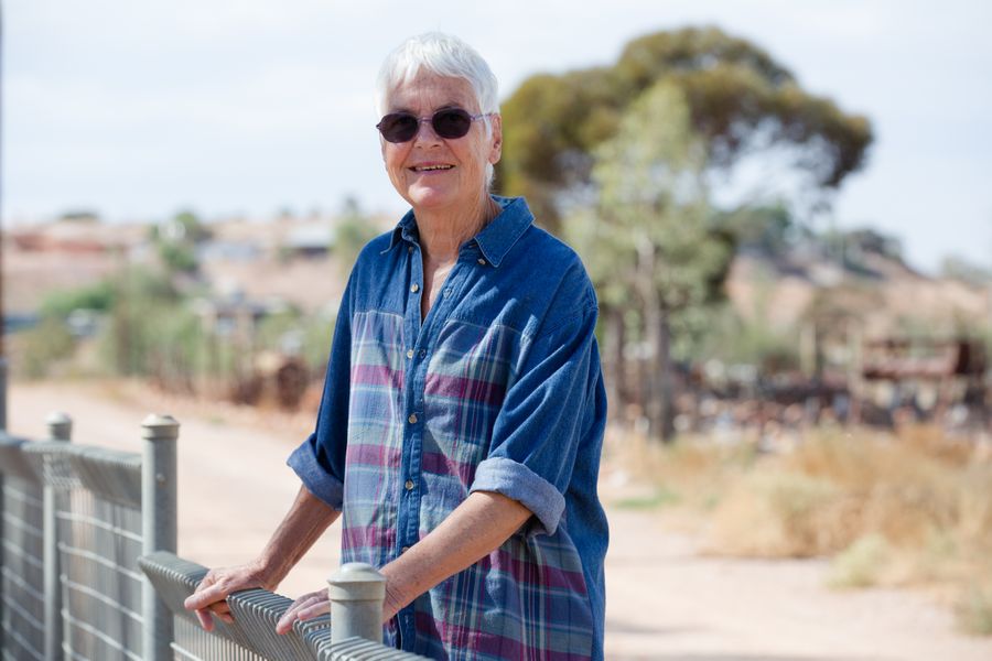 Lady leans on fence in country area
