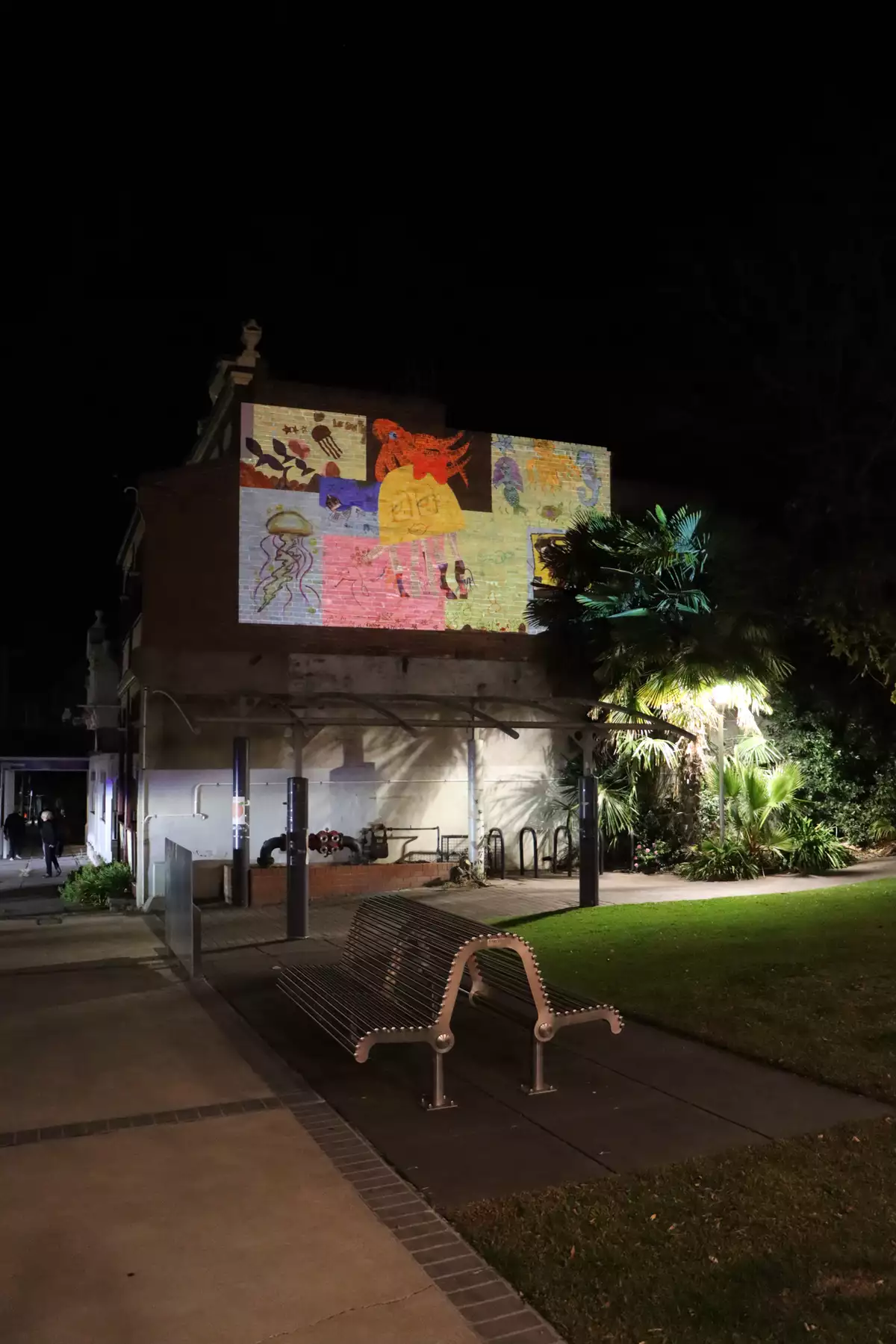photo of collage projected on wall in forecourt after dark