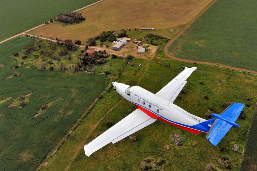 RFDS aircraft flies over green paddocks. 