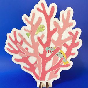 A hand painted pink coral ornament standing on a blue table