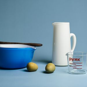 A glass representation of a blue mixing bowl, white water jug, 2 green eggs and 1 x pyrex measuring