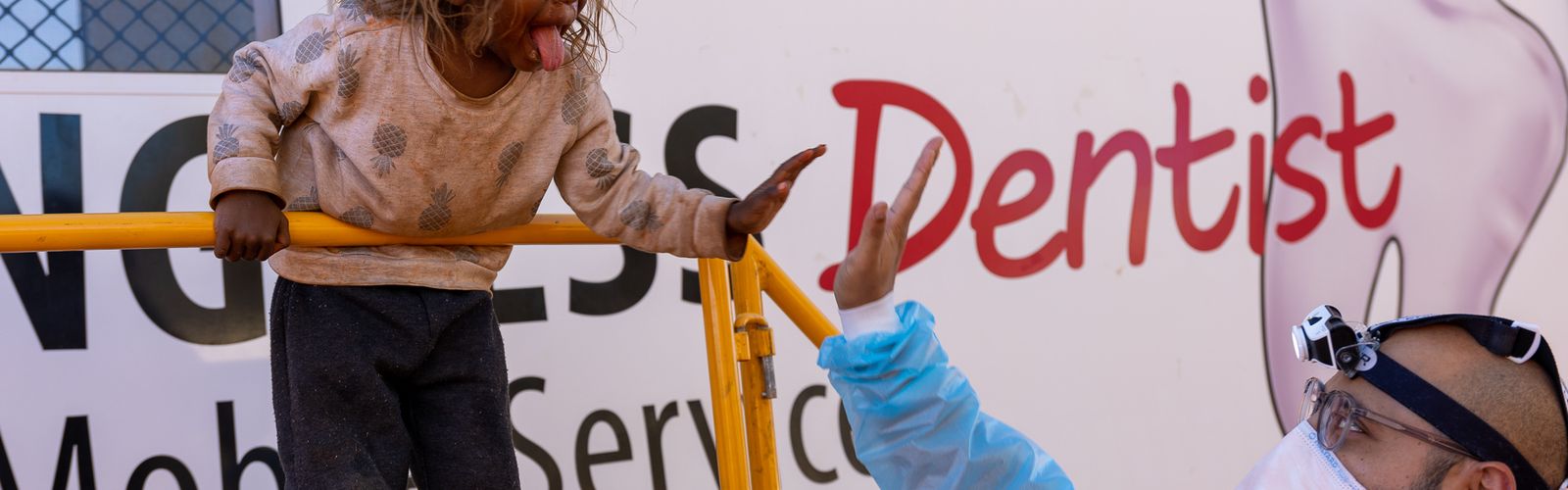 Dr Vai is pictured with a patient in a dentist's chair in Alice Springs