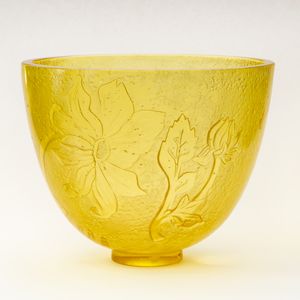 a large yellow glass bowl intricately carved with flowers