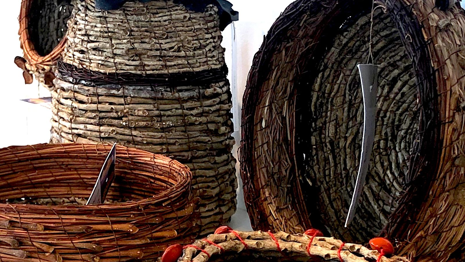 A collection of hand woven natural fibre baskets sitting on a white shelf in the window of Object Shop.