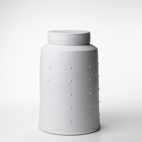 A narrow, white ceramic vessel on a white background