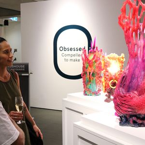 Man and woman looking at large pink phoenix made from resin on plinth.