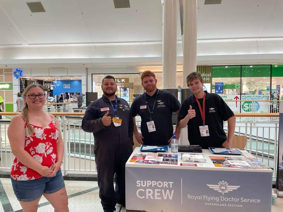 Two men stand behind a table as they fundraise for RFDS