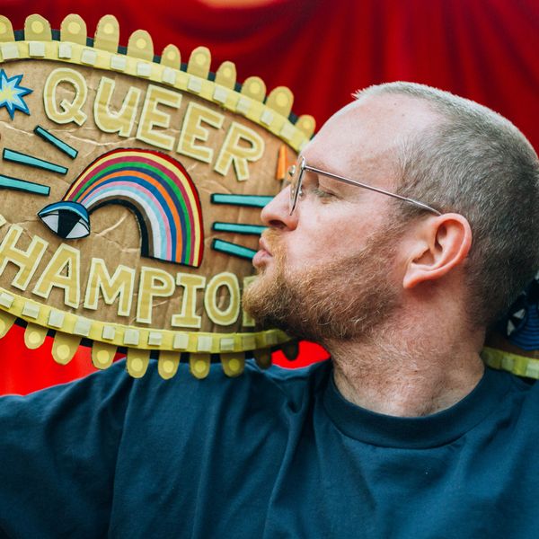 Photo of the artist kissing his 'Queer Champion' titled weight belt made from hand painted cardboard