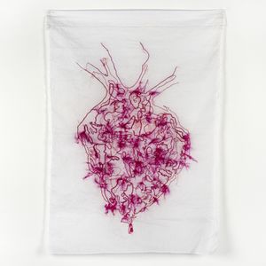 An embroidery of a red and pink anatomical heart, containing loose threads and fibres