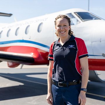 A nurse in a RFDS polo shirt smiles at the camera