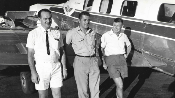 3 men are standing in front of an RFDS aircraft. Liane's father is on the right hand-side leaning against the plane. The image is in black and white.
