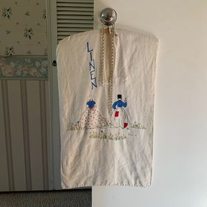 An embroidered linen laundry bag hangs from a door knob