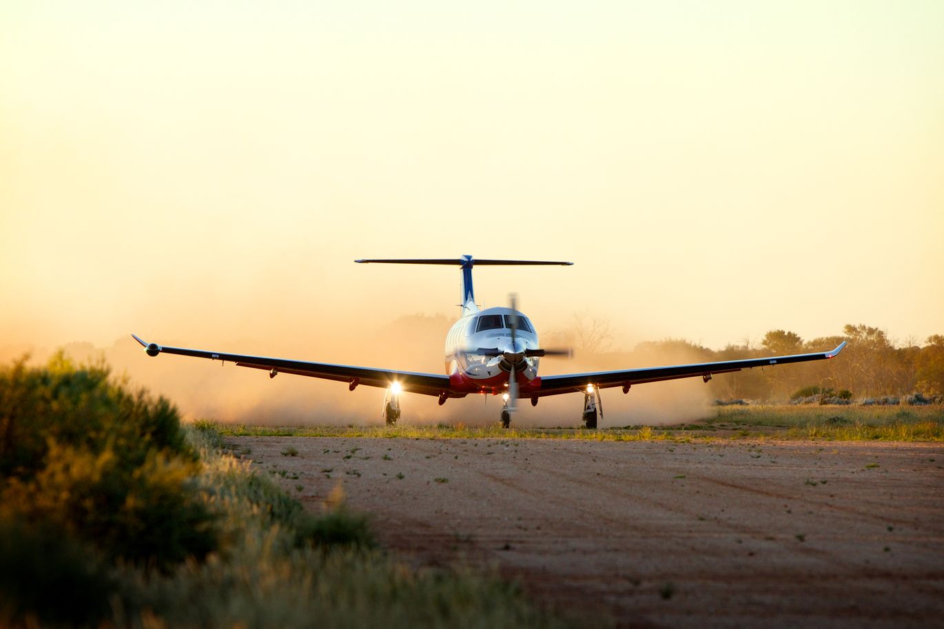 A RFDS aircraft is stationary on red dirt. 