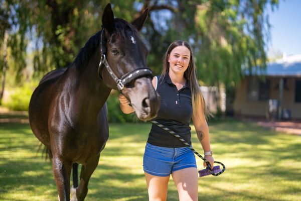 Bella smiling next to a horse