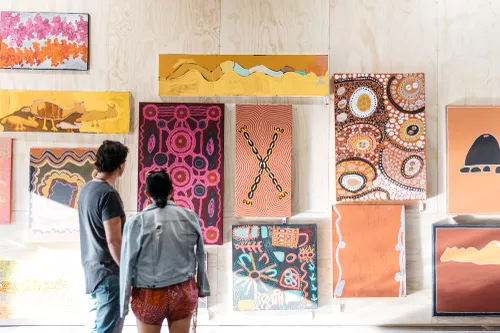 Two people look at artwork in an art market