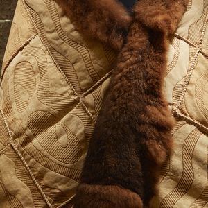 A close-up photograph of a possum skin claok with intricate designs and possum fur
