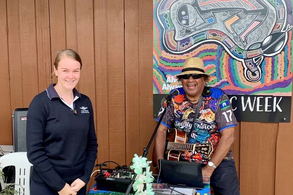 Community members gather around an RFDS plane on a dirt runway