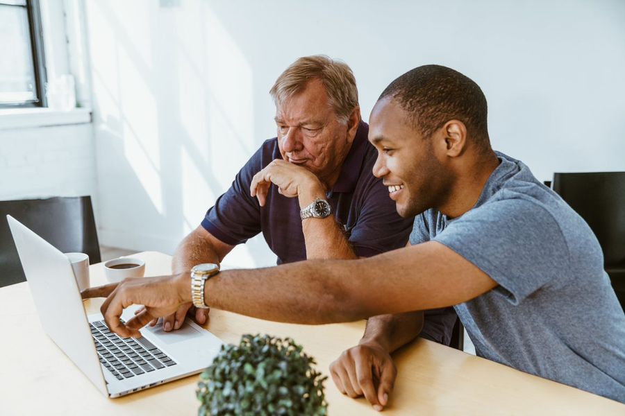 Two middle-aged men looking at a laptop computer