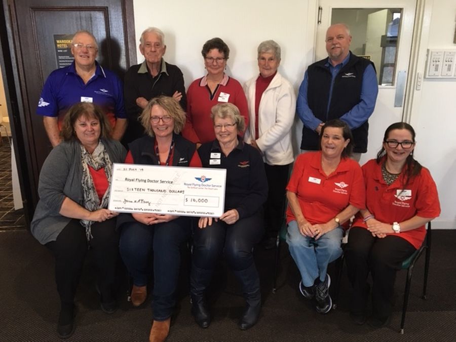 A group of people holding an oversized cheque smile at the camera. 