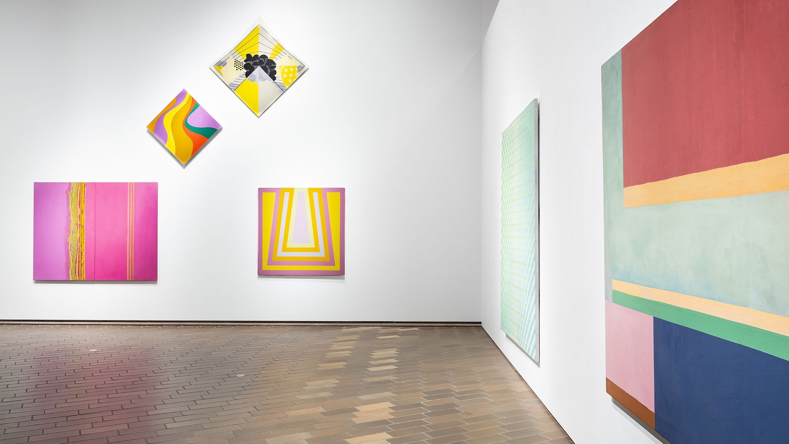 Wide angle photograph of brightly coloured abstract paintings on gallery walls