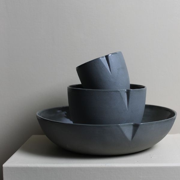 A stack of dark charcoal coloured ceramic bowls sitting on a table.