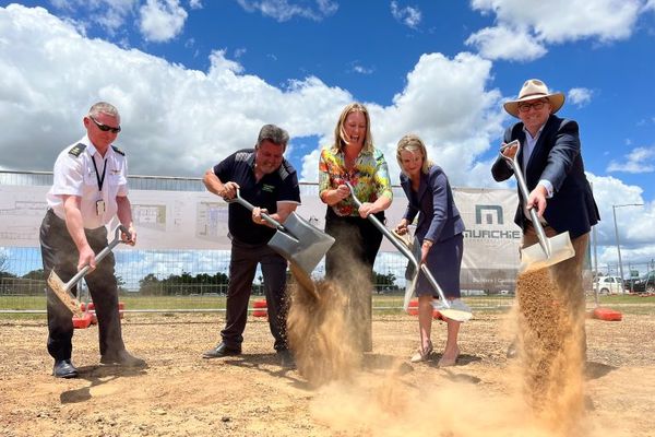 Five people using shovels dig up dirt on the site of the new aviation training facility.