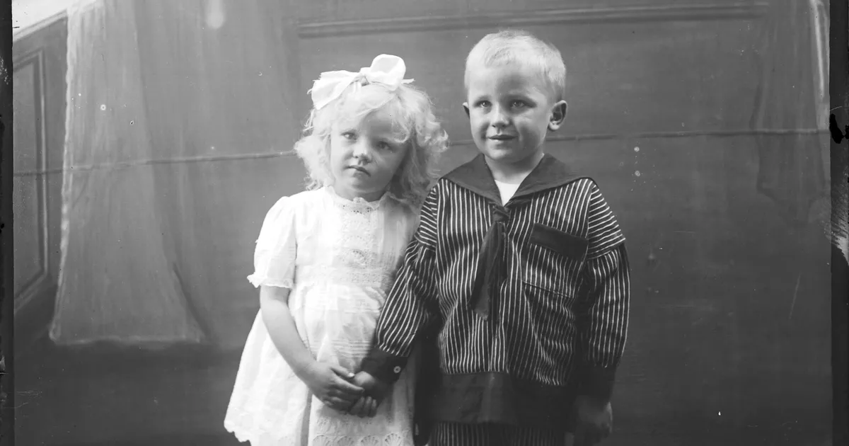 Studio portrait of little boy and girl holding hands - AGSA Collection
