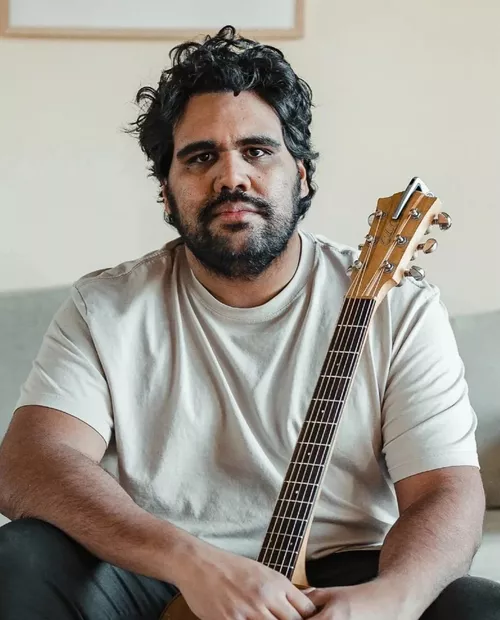 A man in a white shirt poses with a guitar