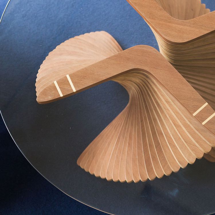 Photo of a glass topped coffee table with boomerang shaped wooden supports.