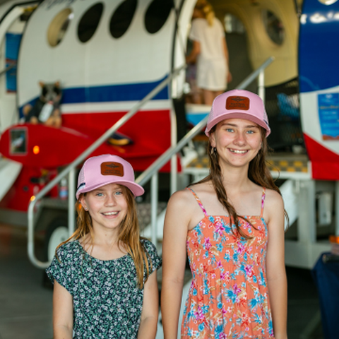 two girls looking at the camera wearing RFDS caps