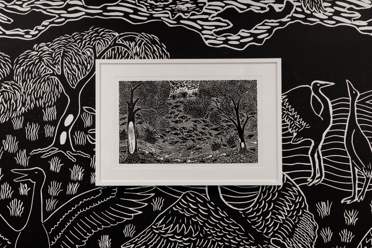 A framed black and white print is displayed on top of a black and white wallpaper.