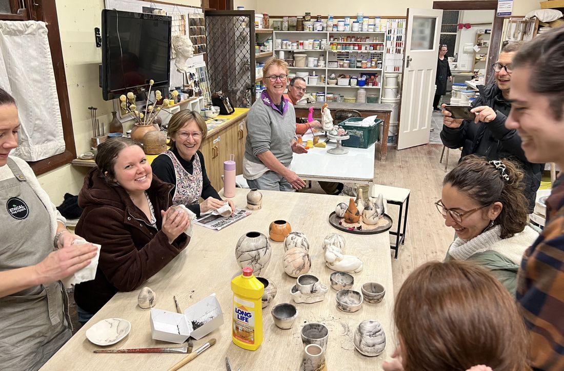 A group of the Macquarie Hills Potters in the Studio sitting at a table, smiling