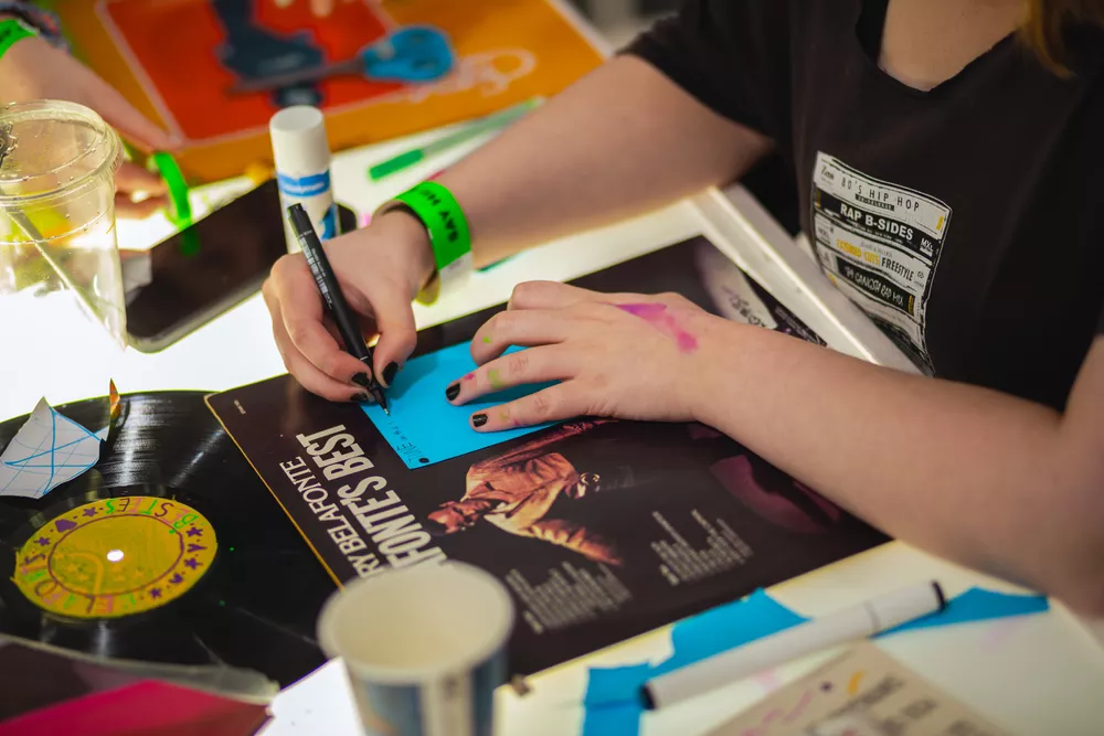 Young person decorating vinyl record cover with pen.
