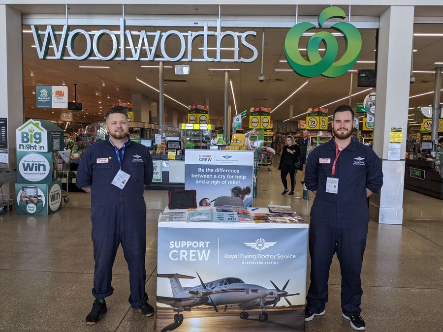 Two men stand proudly in dark blue overalls.