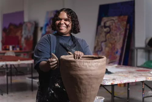 A First Nations artist poses with her clay artwork