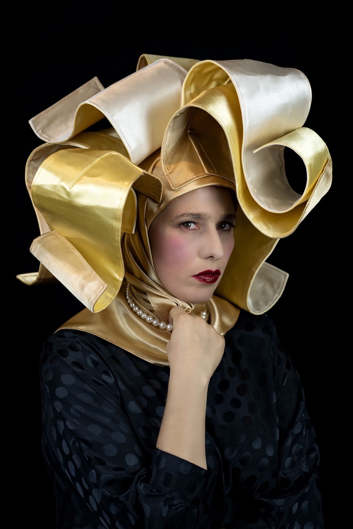 An image of a woman wearing an elaborate gold headers looking directly at the camera.