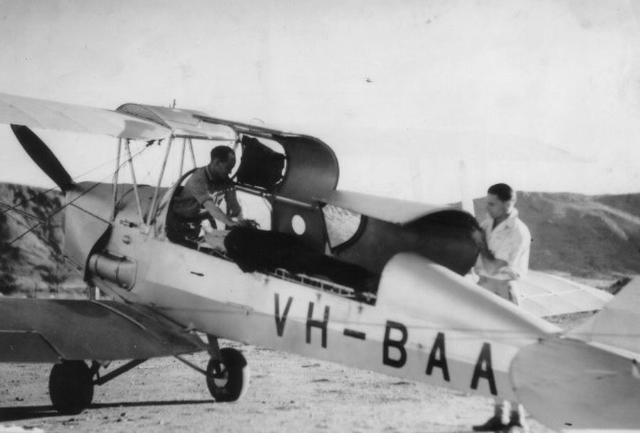 Historical photo of DH-83 Fox Moth plane and two RFDS staff preparing for flight