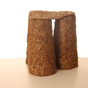 A brown three legged stool made of straw on a white background