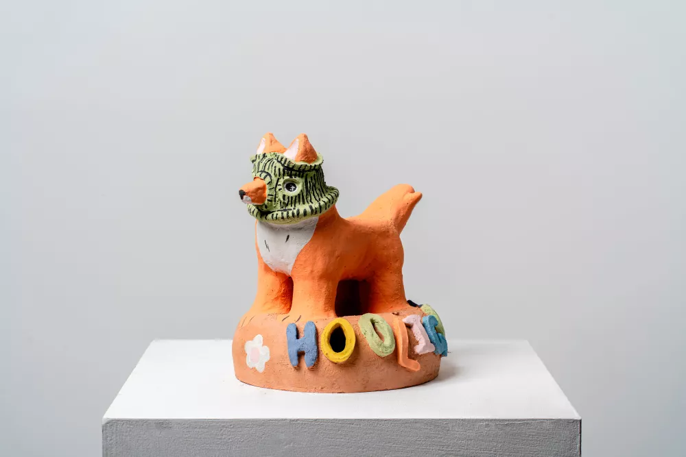 A ceramic figure of a fox wearing a balaclava with the word "hooligan" fixed to the base