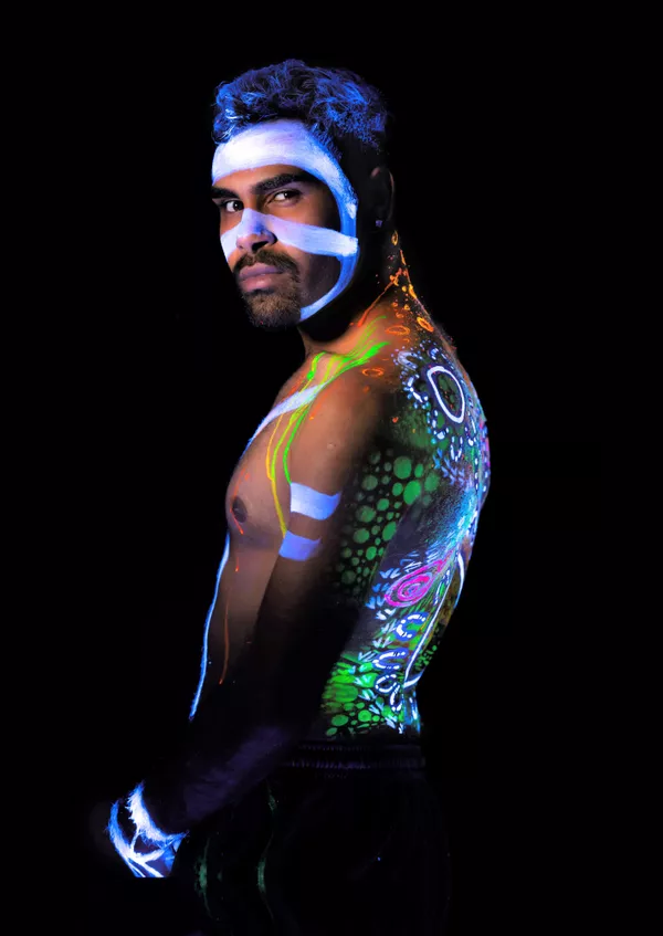 A First Nations man poses with UV paint covering him