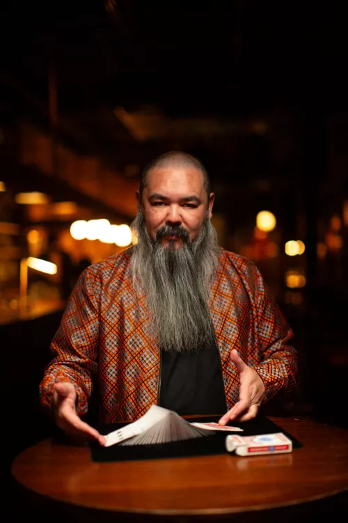 A bearded man poses with a deck of cards