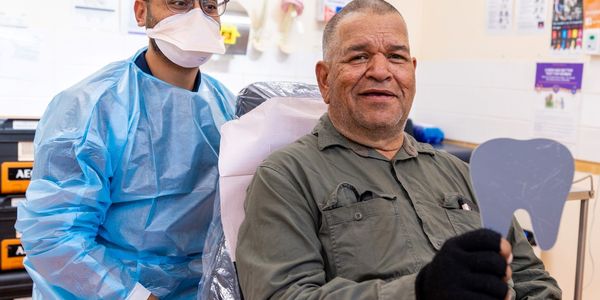 Dr Vai is pictured with a patient in a dentist's chair in Alice Springs