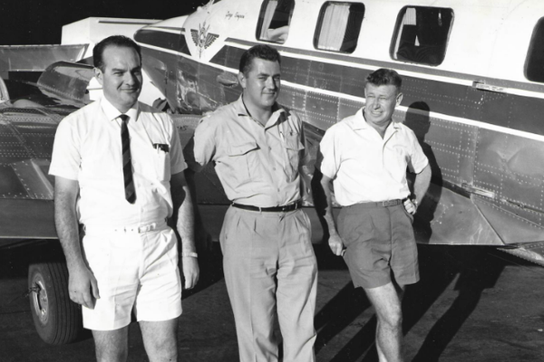 3 men are standing in front of an RFDS aircraft. Liane's father is on the right hand-side leaning against the plane. The image is in black and white.