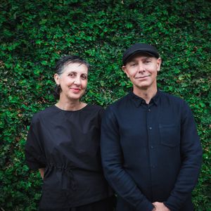A portrait image of Breathe Architecture founders, Tamara Veltre and Jeremy McLeod, wearing black in front of a wall covered in vines