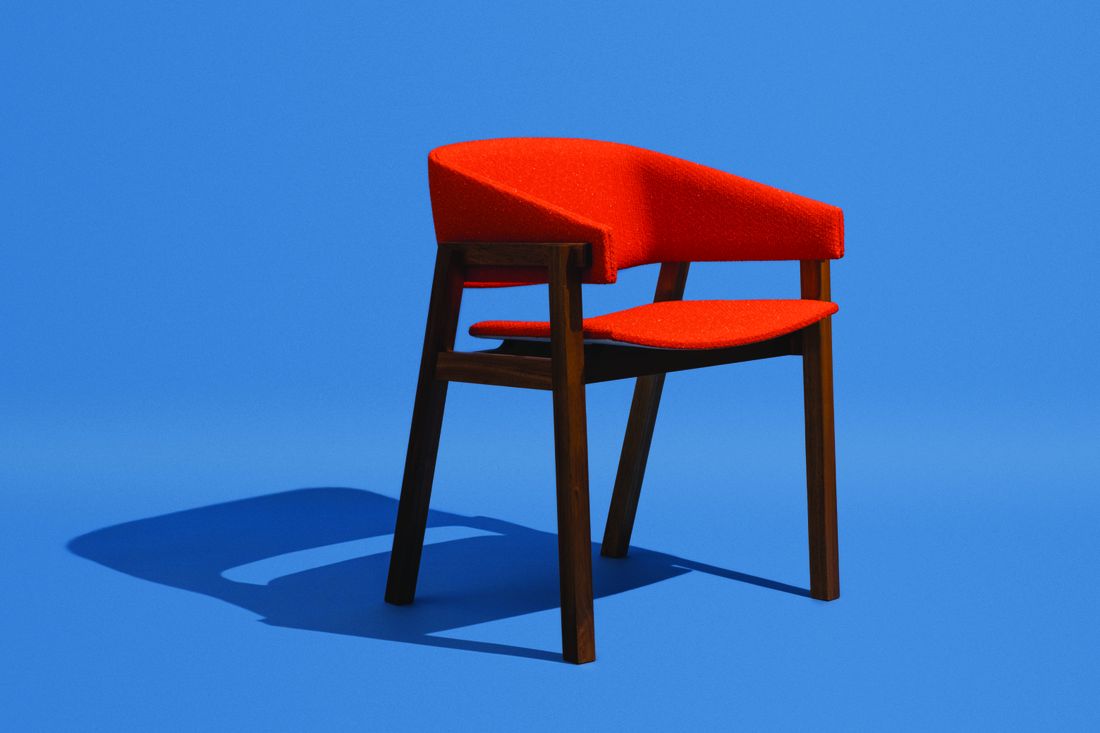 Photo of a wooden dining chair with a red textile backrest and seat on a blue background