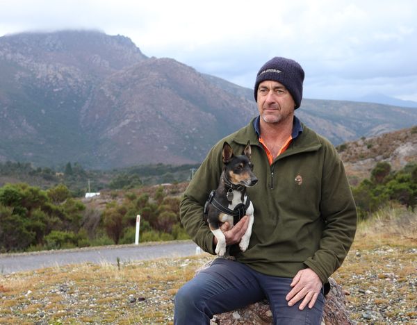Phil and Digger wait for the RFDS Tasmania Health Hub Bus with Queenstown mountains behind.