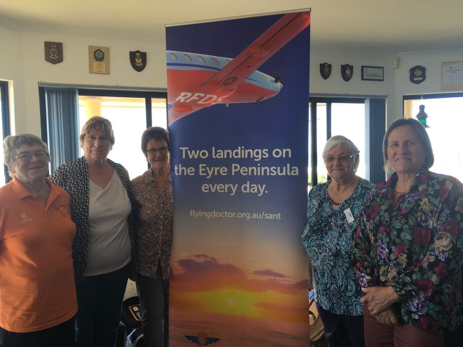 A group of people holding an oversized cheque smile at the camera. The cheque is made out to $20,000 to the RFDS. 